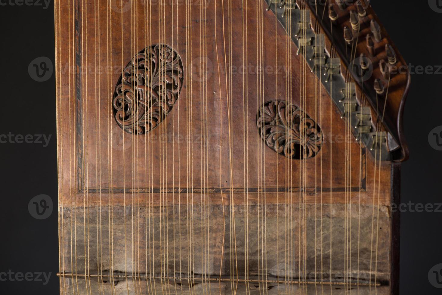 ancient Asian stringed musical instrument on black background with backlight. the similarity of the harp and psaltery. closeup photo