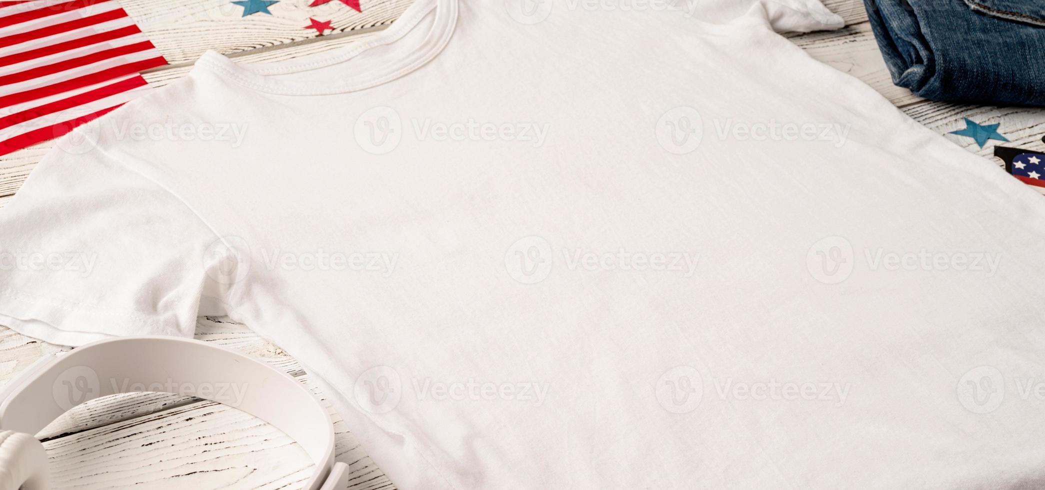 Mockup design white t shirt for logo, high angle view on white wooden background with US flag, shoes and jeans photo