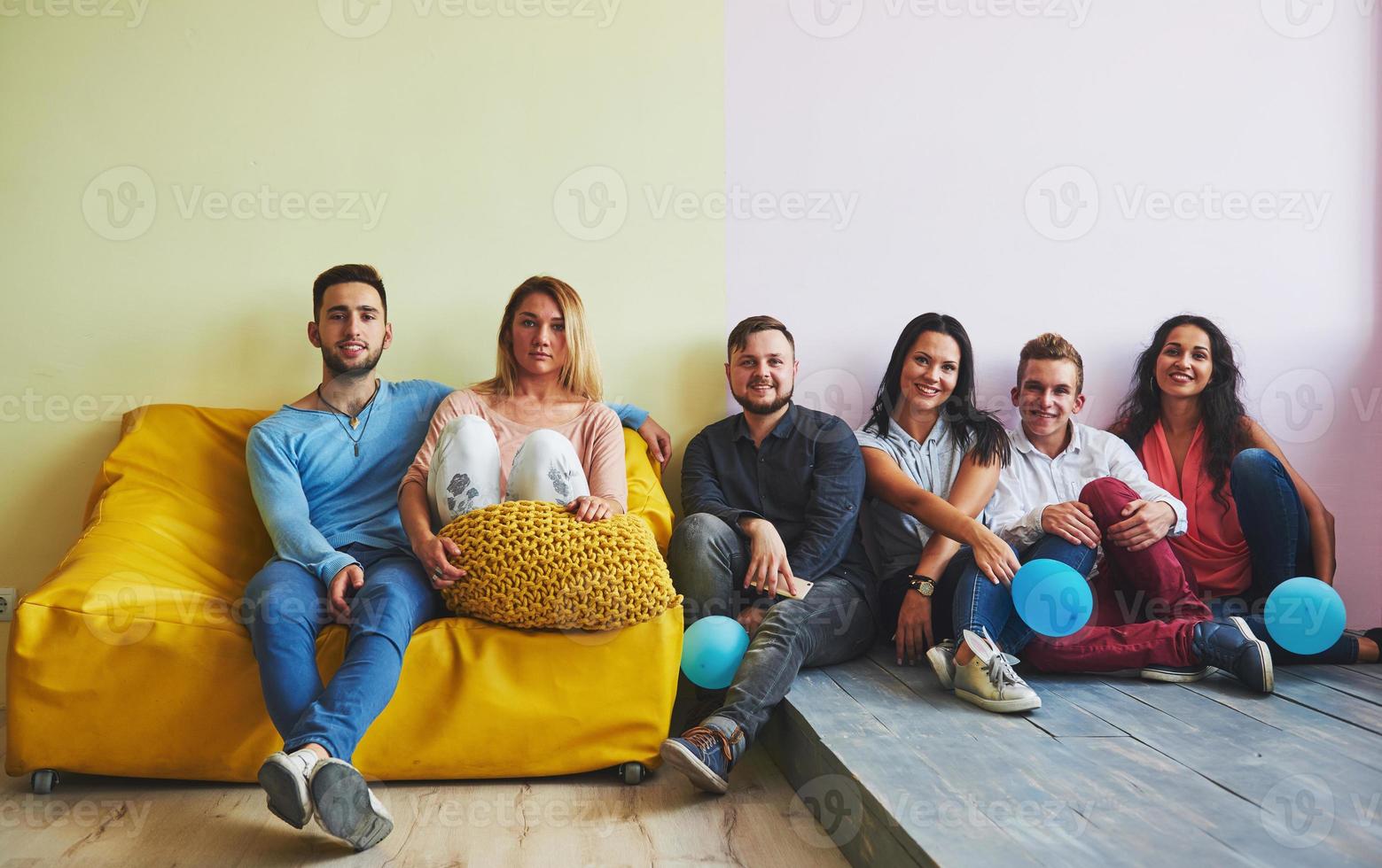 Group portrait of multi-ethnic boys and girls with colorful fashionable clothes holding friend and posing on a brick wall, Urban style people having fun, Concepts about youth and lifestyle photo