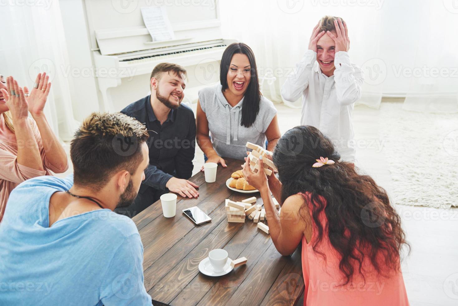 grupo de amigos creativos sentados en la mesa de madera. gente divirtiéndose mientras juega al juego de mesa. foto