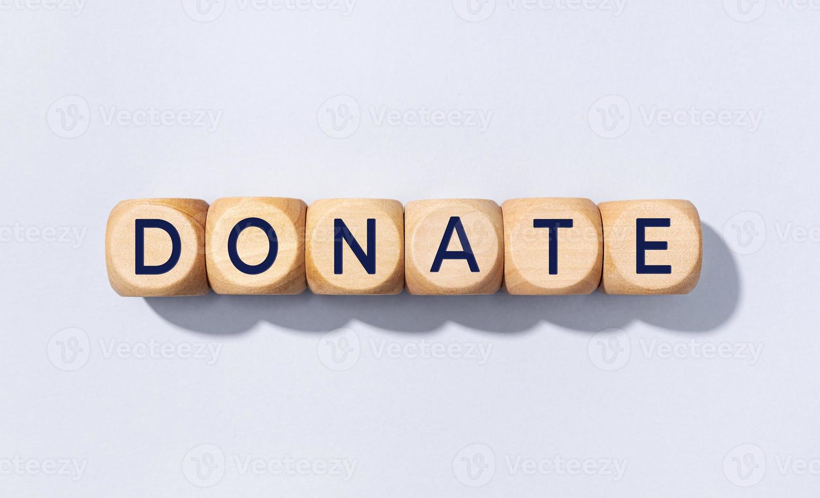 Donate word on wooden block isolated on gray background photo