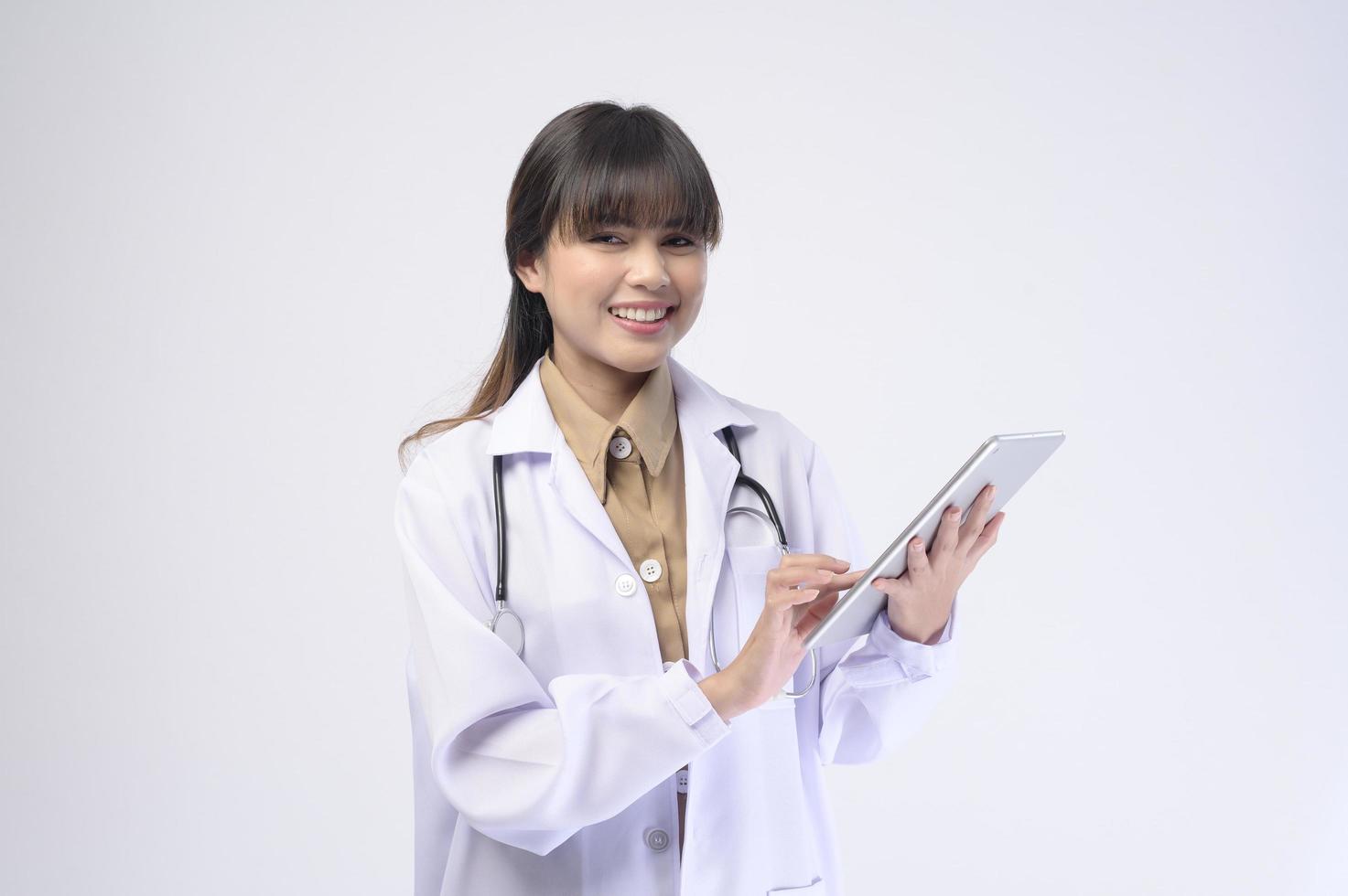 Joven doctora con estetoscopio sobre fondo blanco. foto