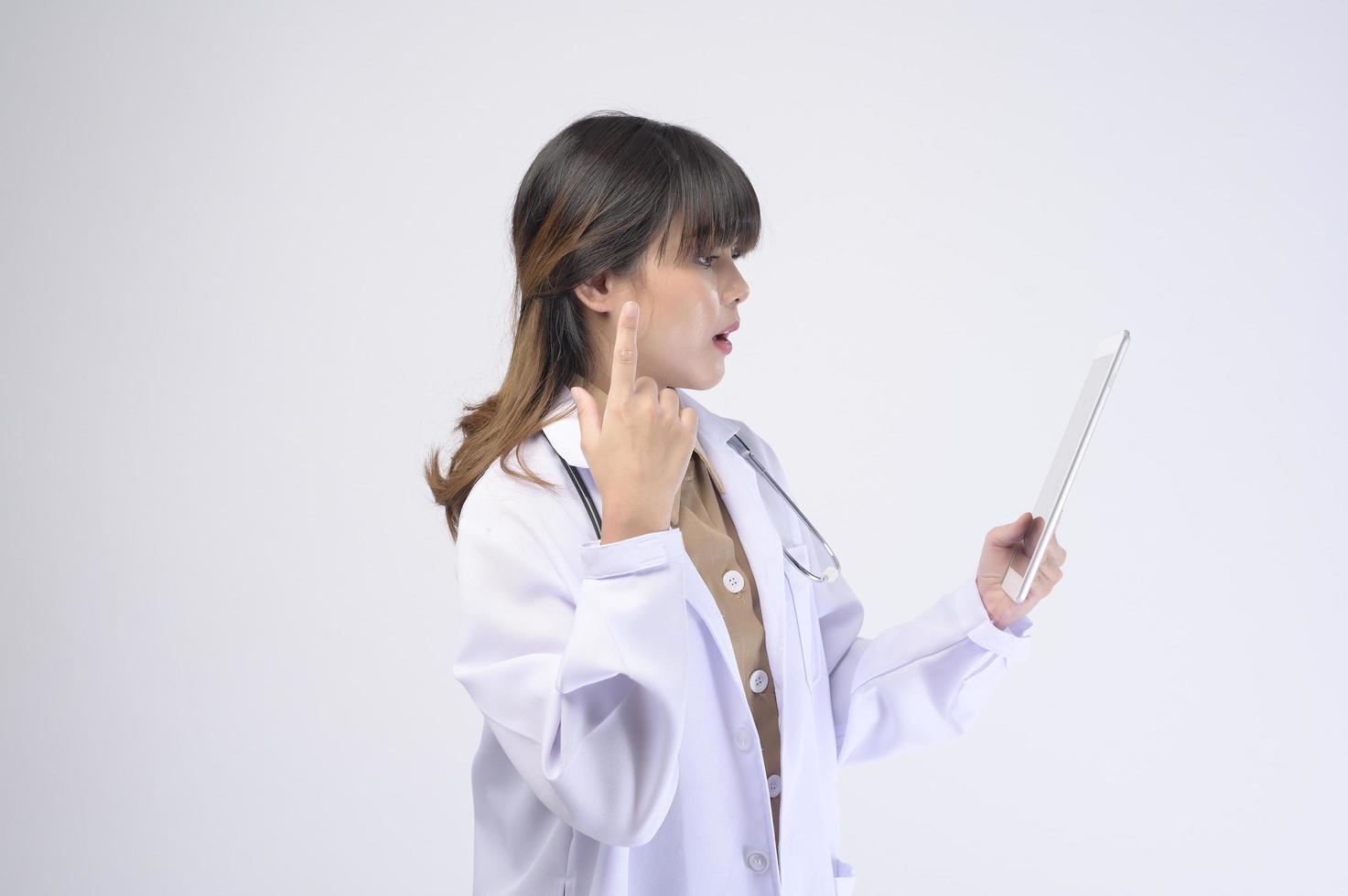 Joven doctora con estetoscopio sobre fondo blanco. foto