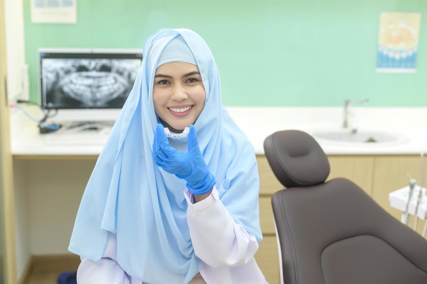 Young female muslim dentist holding invisalign in dental clinic, teeth check-up and Healthy teeth concept photo
