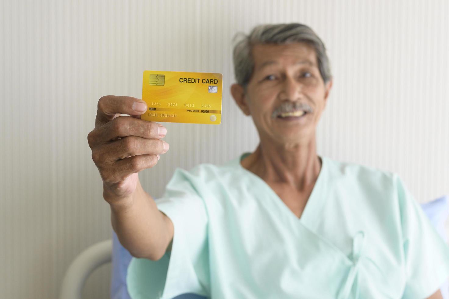 un anciano asiático muestra una tarjeta de crédito en el hospital foto