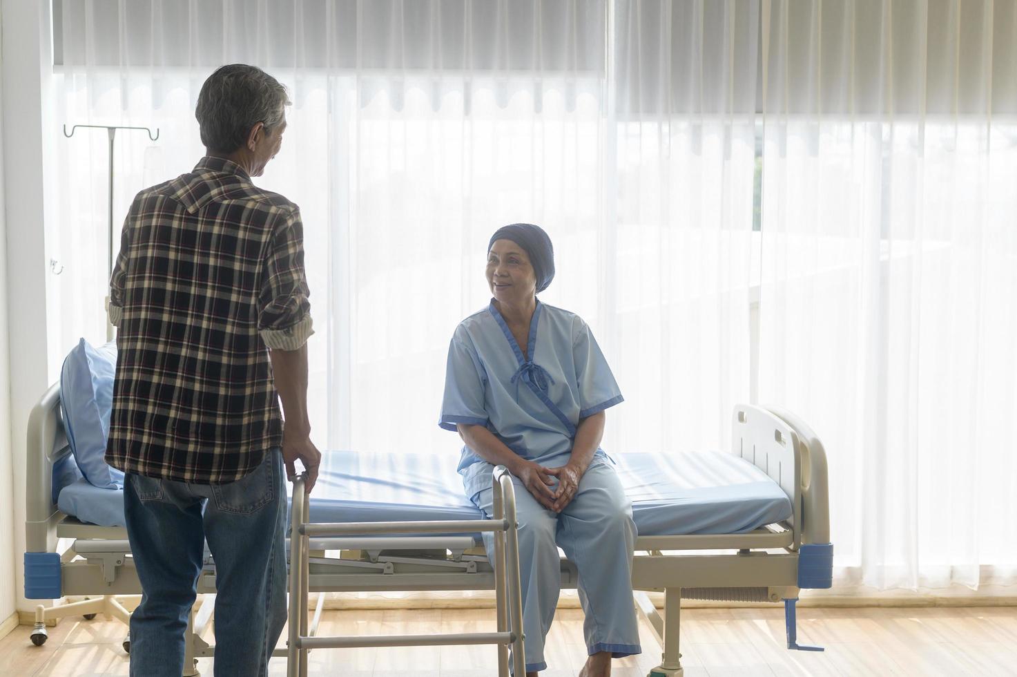 Senior man helping cancer patient woman wearing head scarf with walker at hospital, health care and medical concept photo