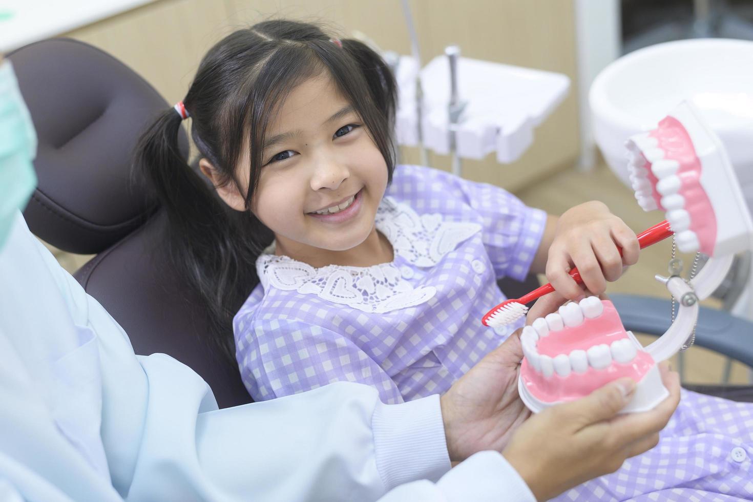 una niña linda con los dientes examinados por un dentista en una clínica dental, un chequeo dental y un concepto de dientes sanos foto