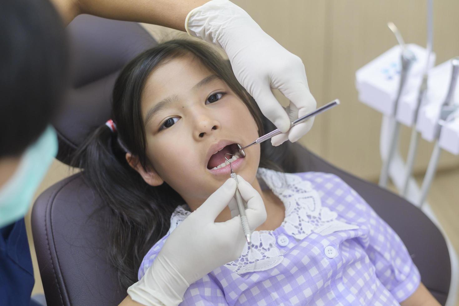 A little cute girl having teeth examined by dentist in dental clinic, teeth check-up and Healthy teeth concept photo