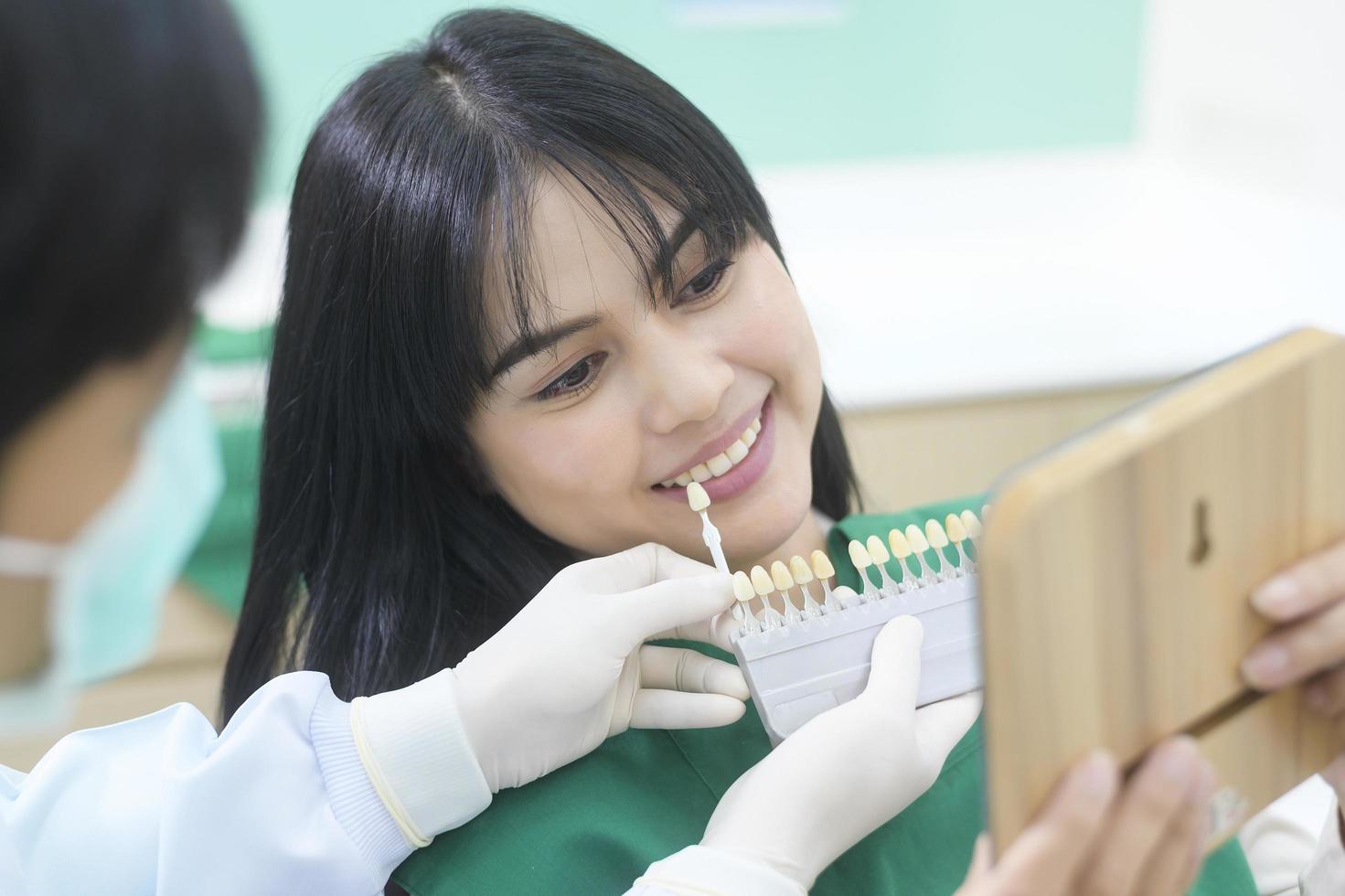 un dentista está examinando los dientes de una paciente usando el nivel de blanqueamiento foto