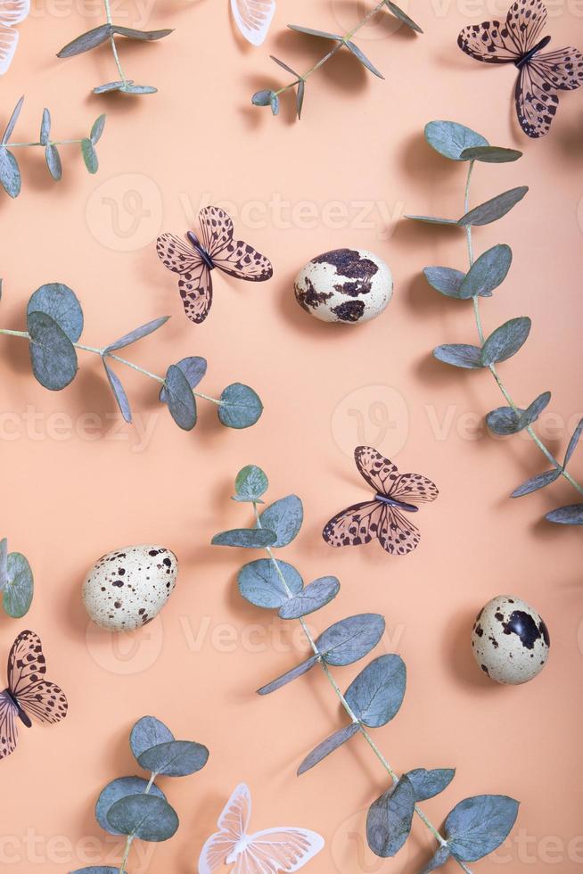 Pattern of Easter eggs, eucalyptus, butterflies and beads. Trendy flat lay composition on color background photo