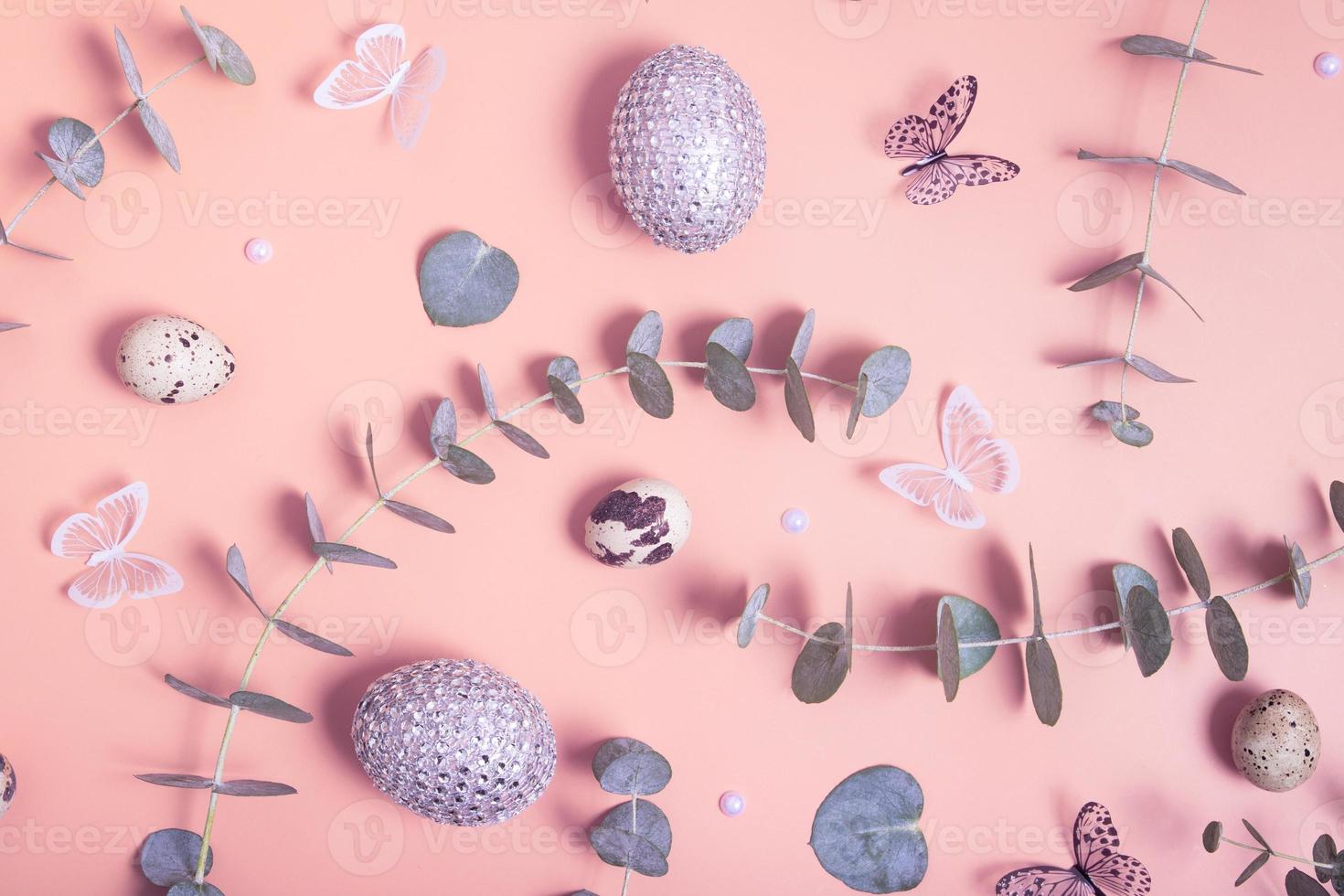 Pattern of Easter eggs, eucalyptus, butterflies and beads. Trendy flat lay composition on color background photo