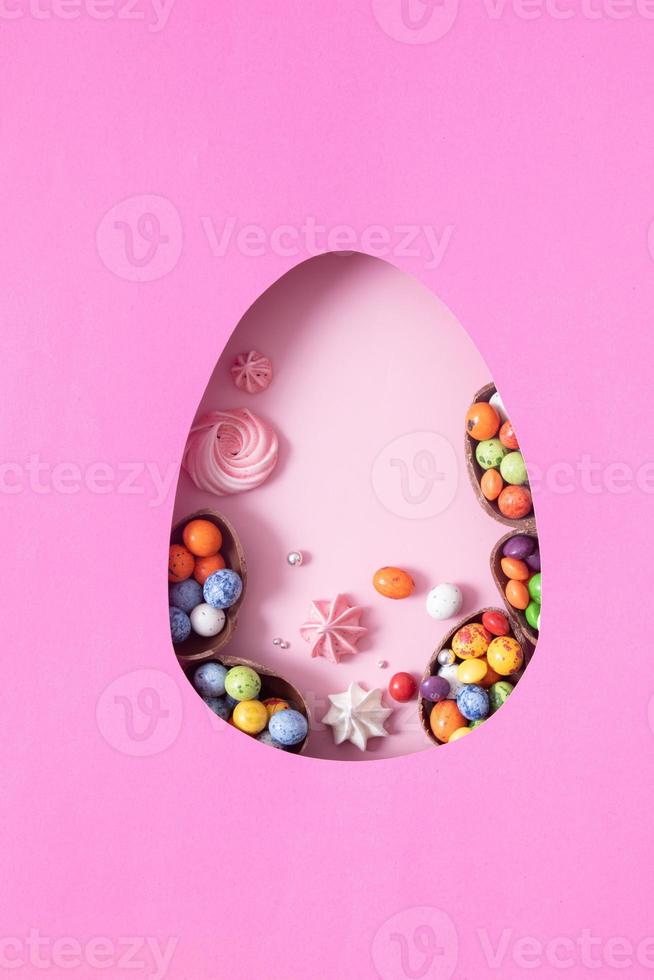 Chocolate easter eggs and decor flat lay for kids easter hunt egg concept on pink background. Sweets in the shape of an egg photo