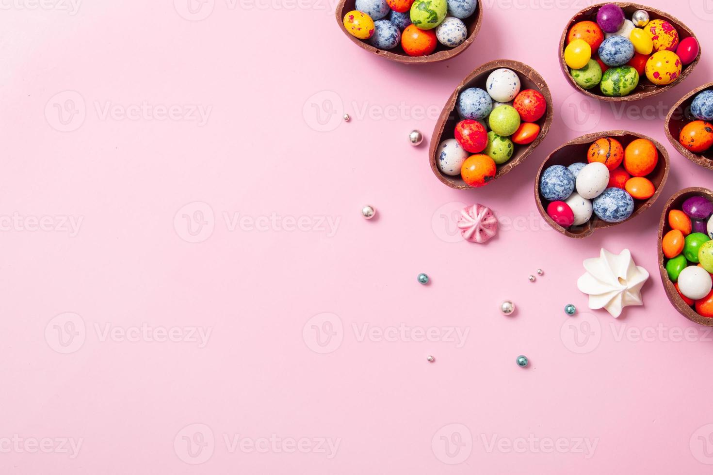 Chocolate easter eggs and decor flat lay for kids easter hunt egg concept on pink background. Sweets in the shape of an egg photo