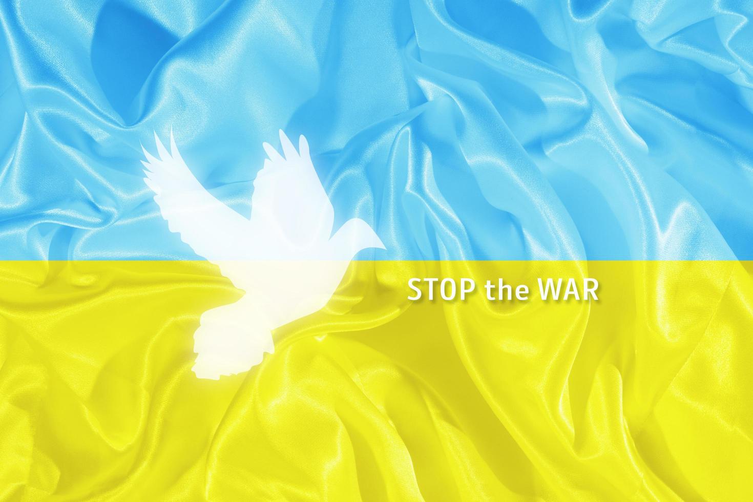 Stop the war text on the blue and yellow Ukrainian flag with the silhouette of the dove of peace photo