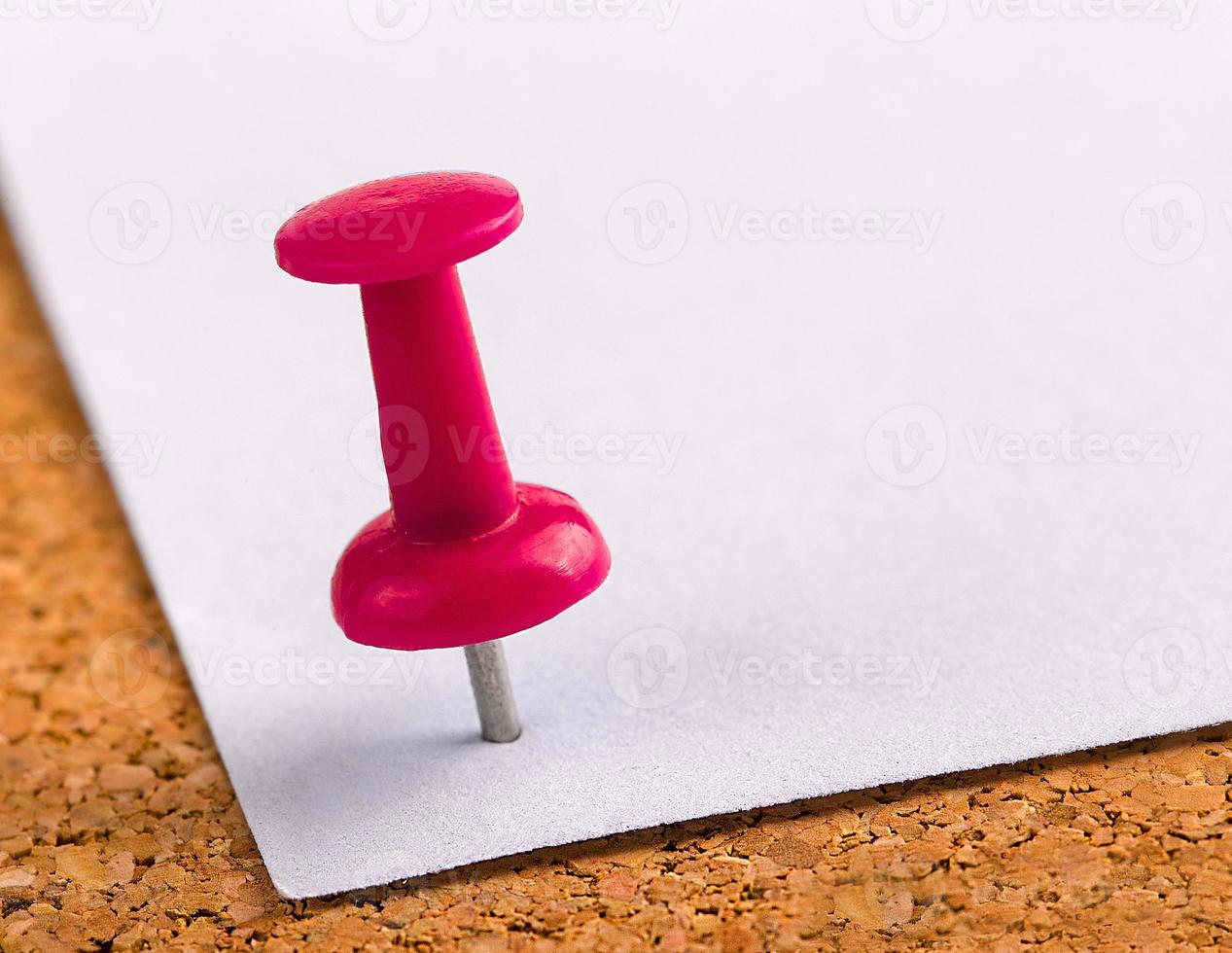 plastic button with a needle stuck in an iron sheet of white paper on a wooden stopper photo