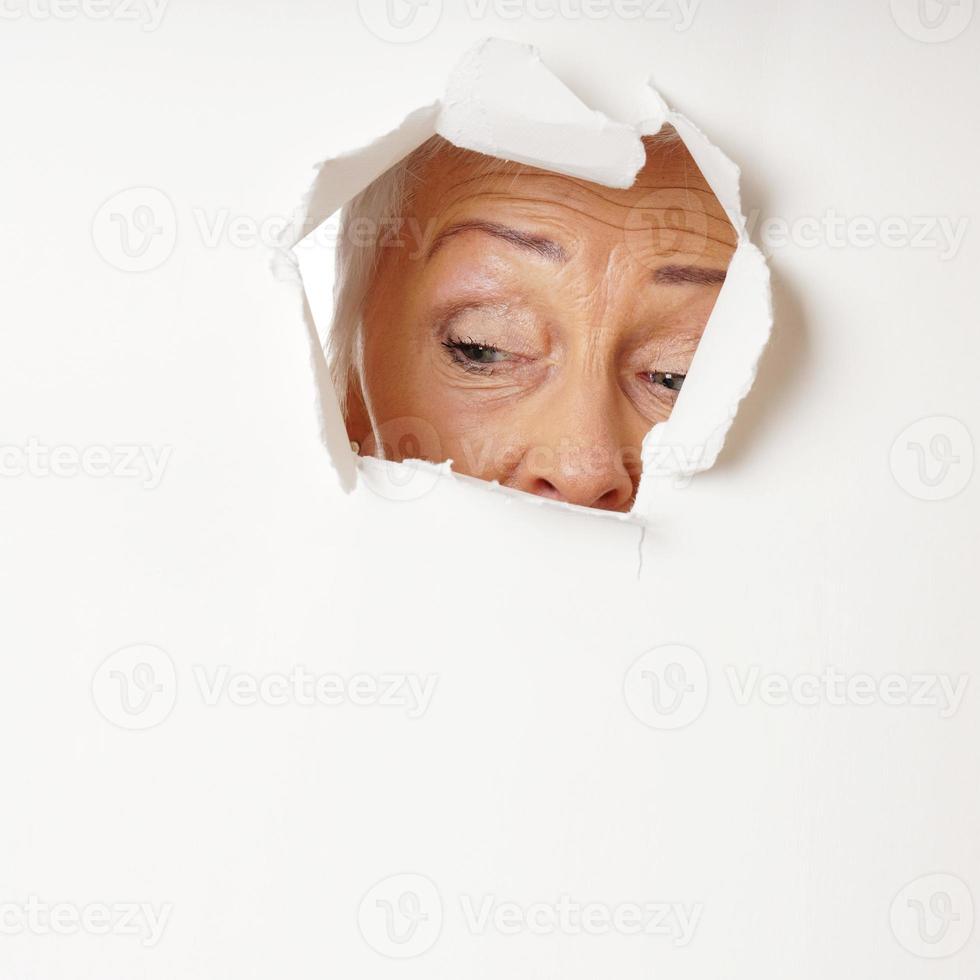 curious mature woman looking through hole photo