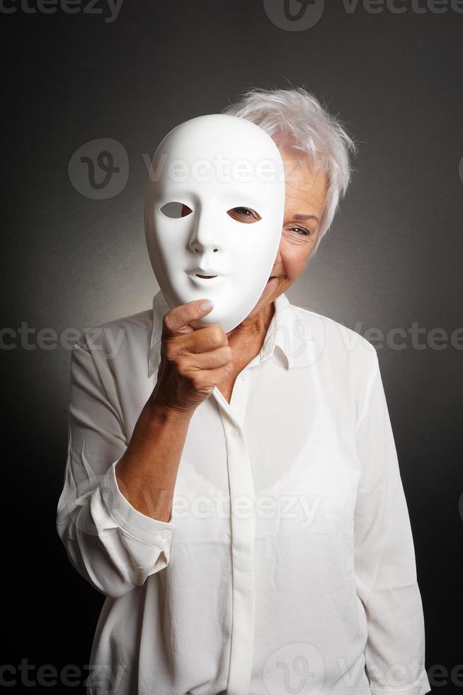 happy mature woman peeking from behind mask photo