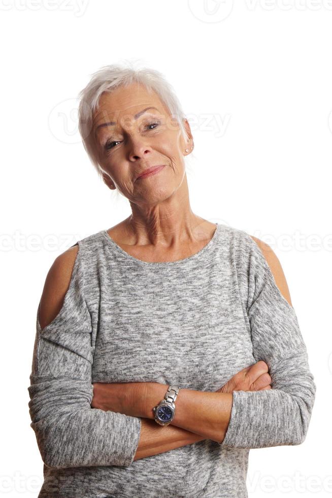 mature woman with arms folded and head tilted photo