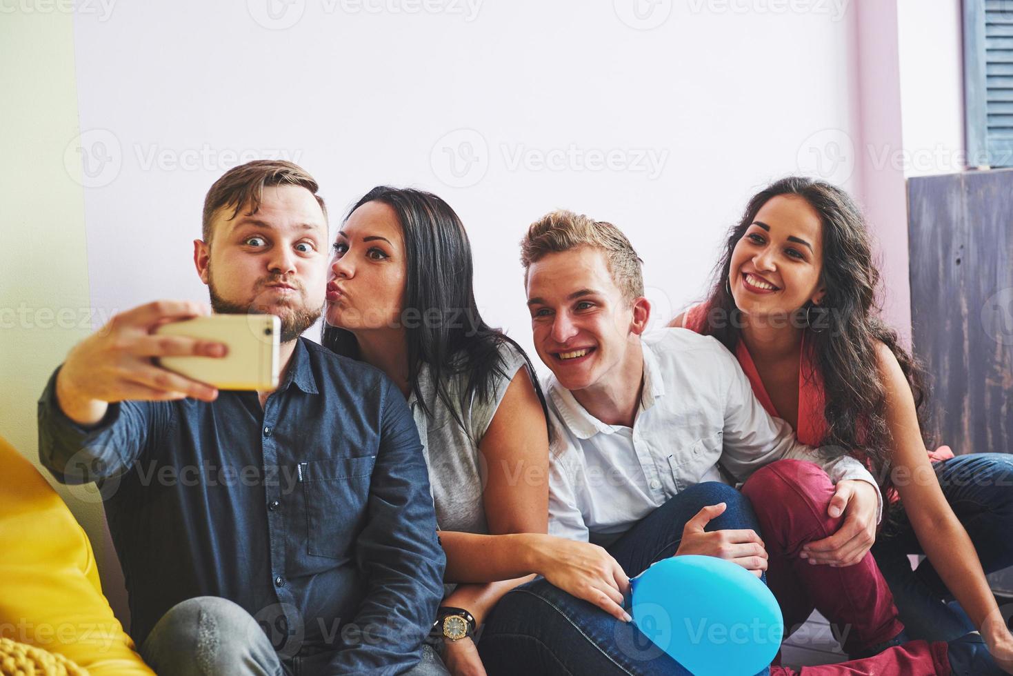 Group portrait of multi-ethnic boys and girls with colorful fashionable clothes holding friend and posing on a brick wall, Urban style people having fun, Concepts about youth and lifestyle photo