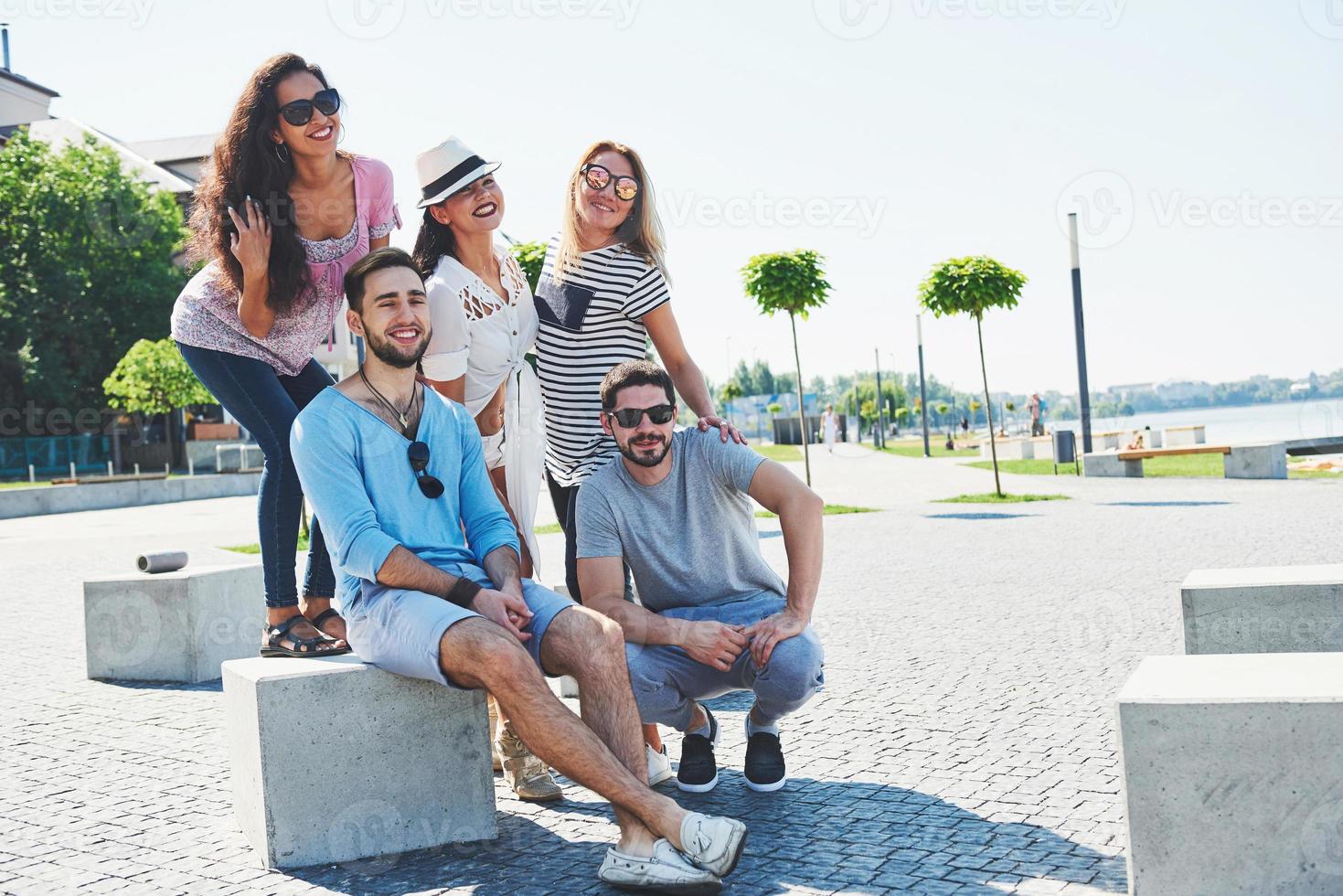 Group of people sitting on a staircase outdoors - Multiracial friends talking and having fun on a meeting outdoors on beach photo
