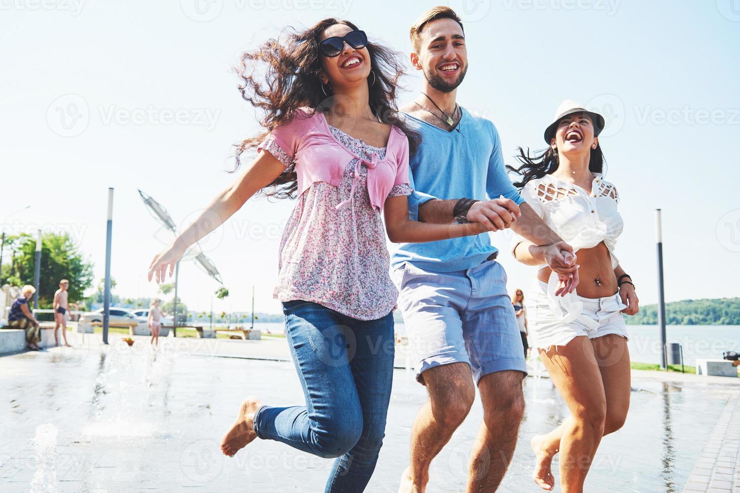 grupo de amigos divirtiéndose junto a la fuente pública el día de verano foto