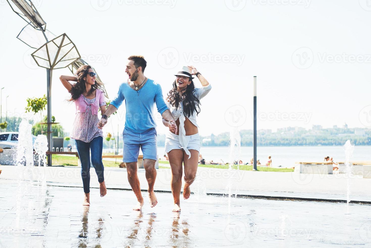 Group of friends having fun next to the public fountain on summer day photo