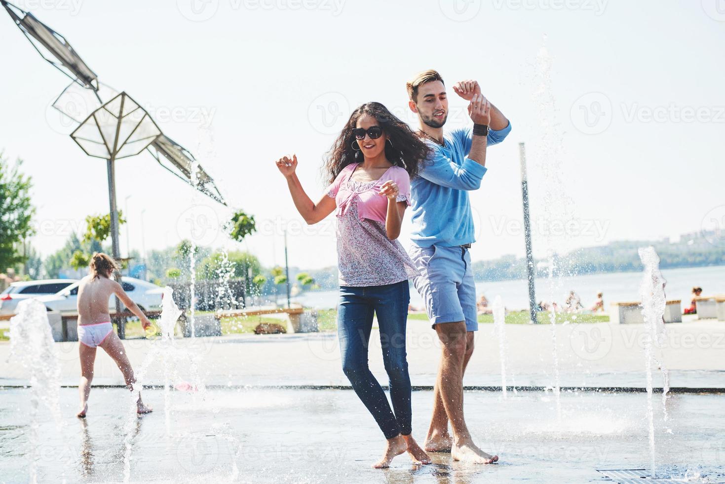 Group of friends having fun next to the public fountain on summer day photo