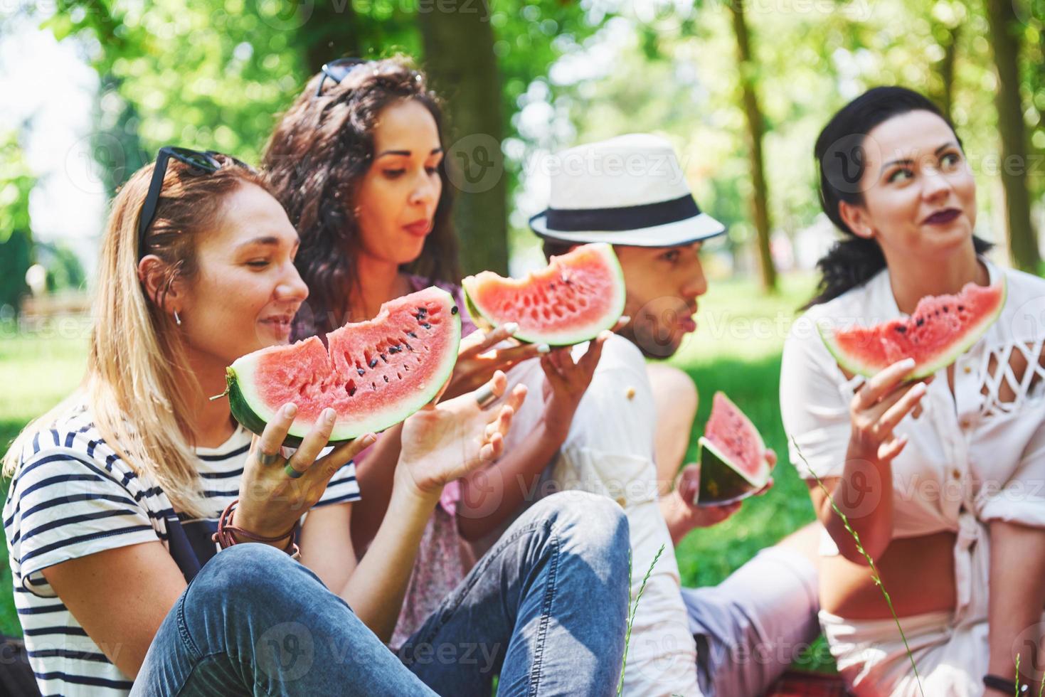 grupo de amigos haciendo un picnic en un parque en un día soleado - gente pasando el rato, divirtiéndose mientras asan y se relajan foto