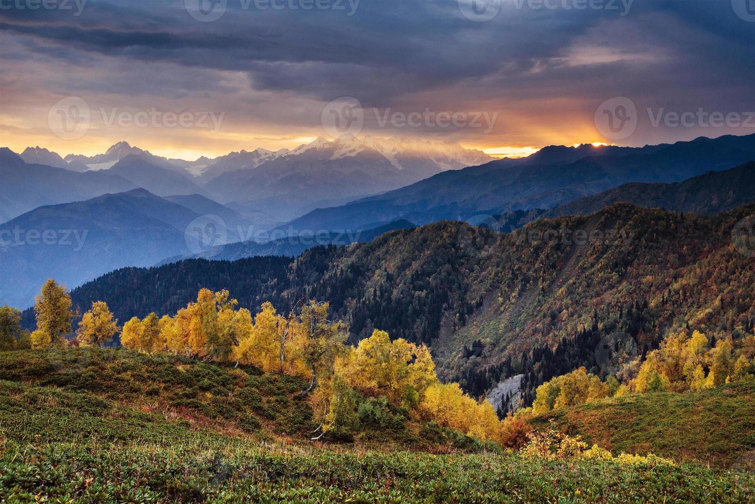 paisaje otoñal y picos montañosos nevados. bosque de abedules a la luz del sol. dorsal caucásica principal. vista a la montaña desde el monte ushba mheyer, georgia. Europa. foto