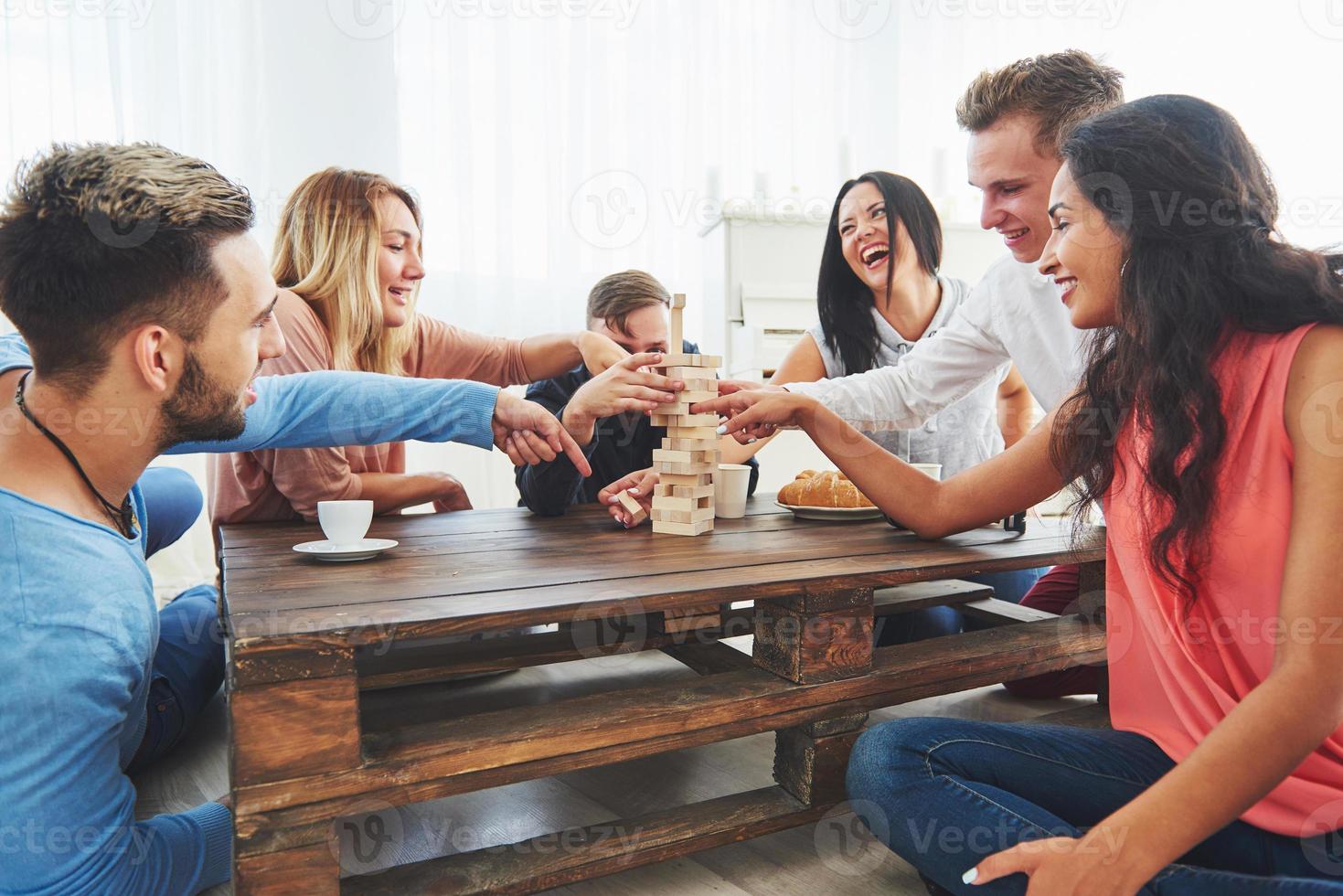 grupo de amigos creativos sentados en la mesa de madera. gente divirtiéndose mientras juega al juego de mesa. foto