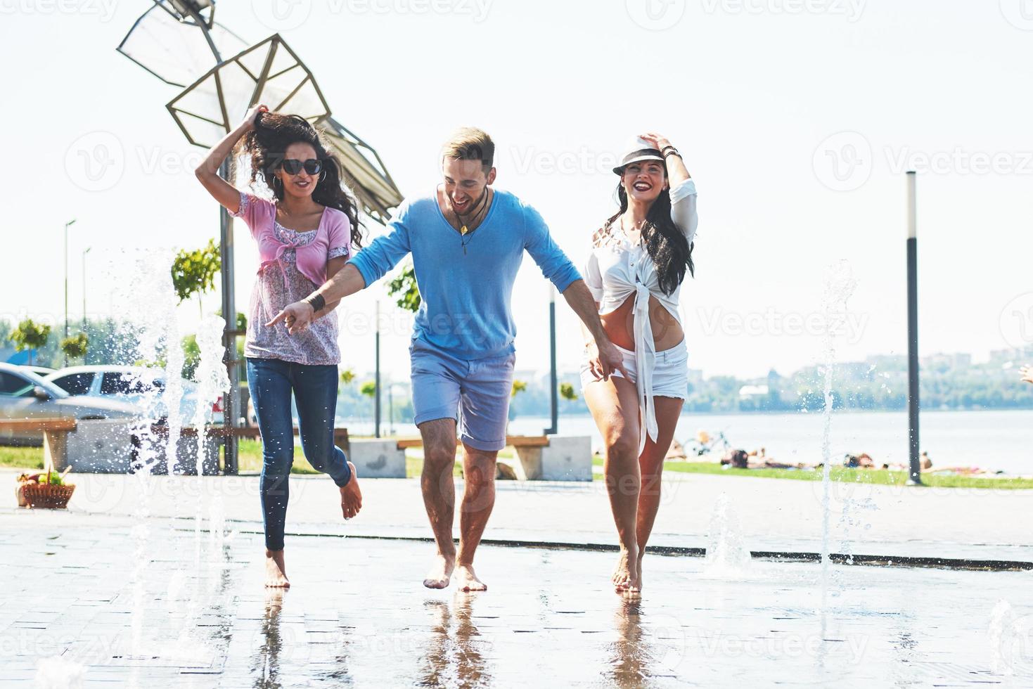 Group of friends having fun next to the public fountain on summer day photo