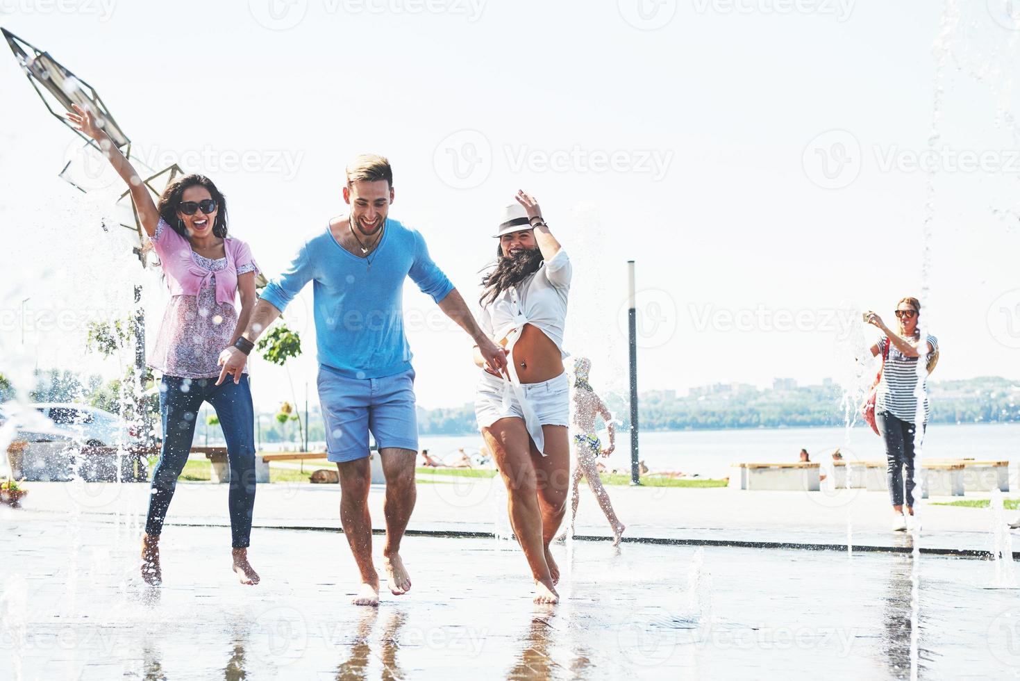 Group of friends having fun next to the public fountain on summer day photo