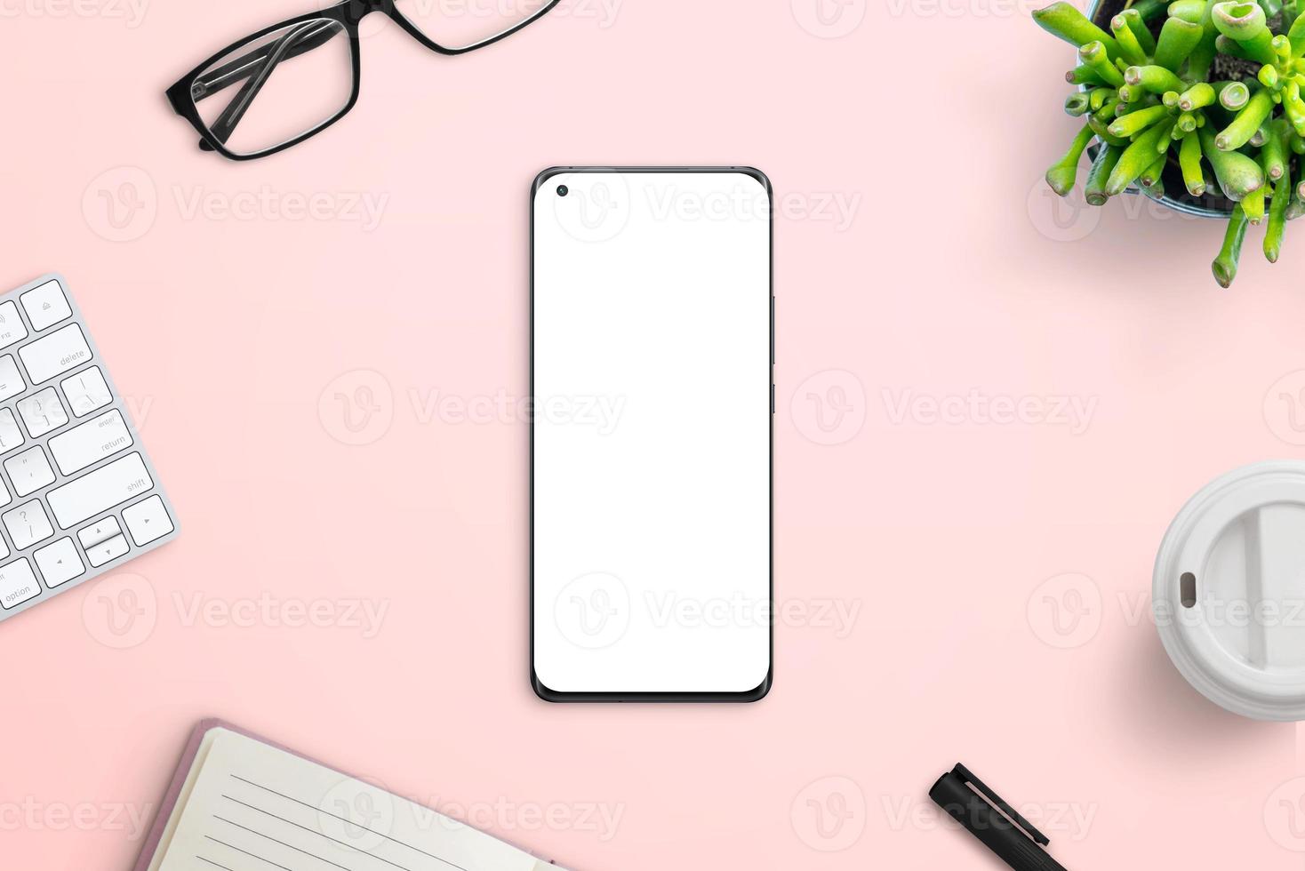 Phone on pink work desk surrounded by office supplies. Clean, flat lay composition for app or web page design promotion photo