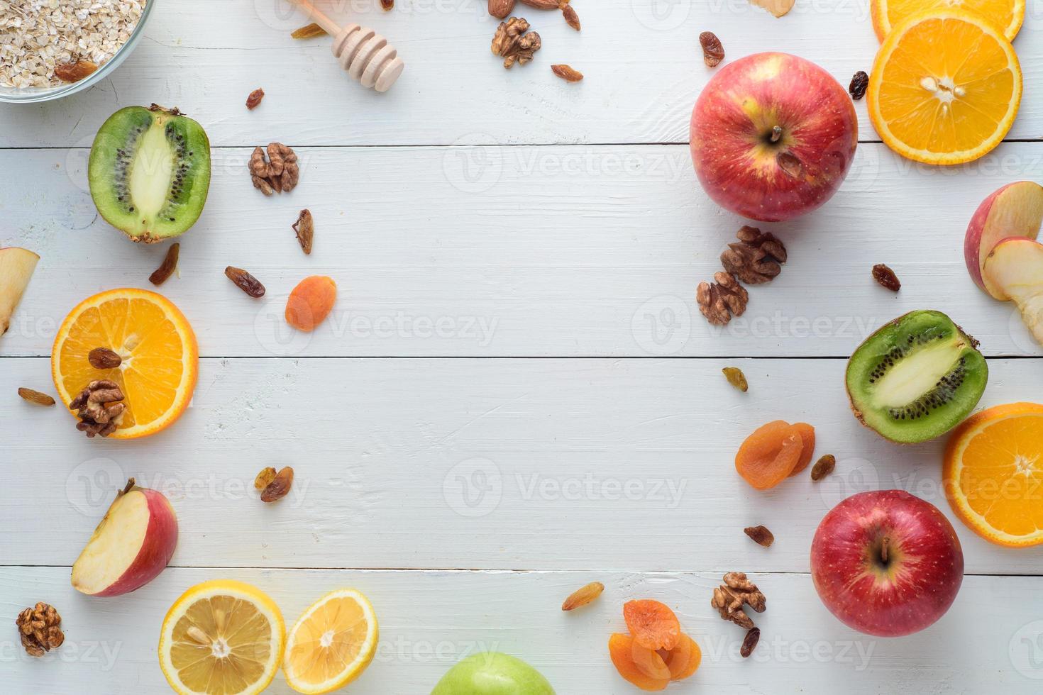 Apples, kiwi fruits, dried fruits, oranges and apples. Healthy eating concept. Shot on a white wooden table. photo