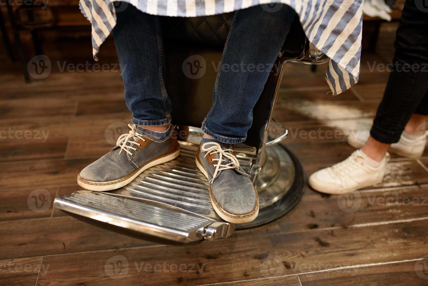 primer plano de las piernas del hombre en la silla de peluquero foto