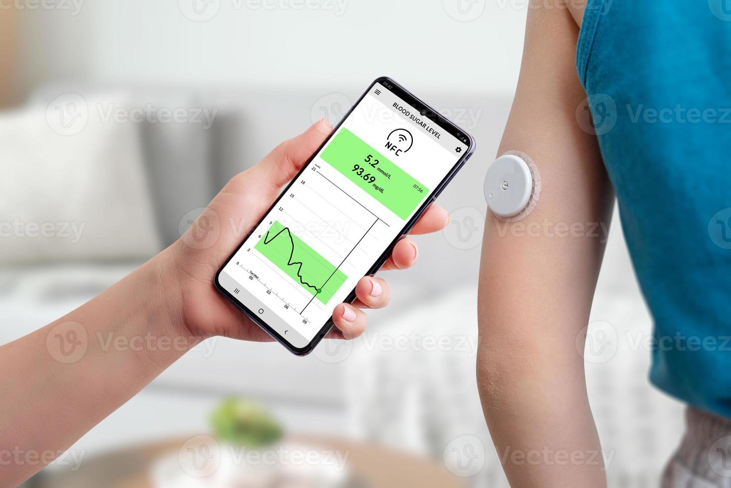 Measurement of blood glucose with the help of mobile app and sensor. Hand brings the phone closer to the sensor located on the child's hand concept photo