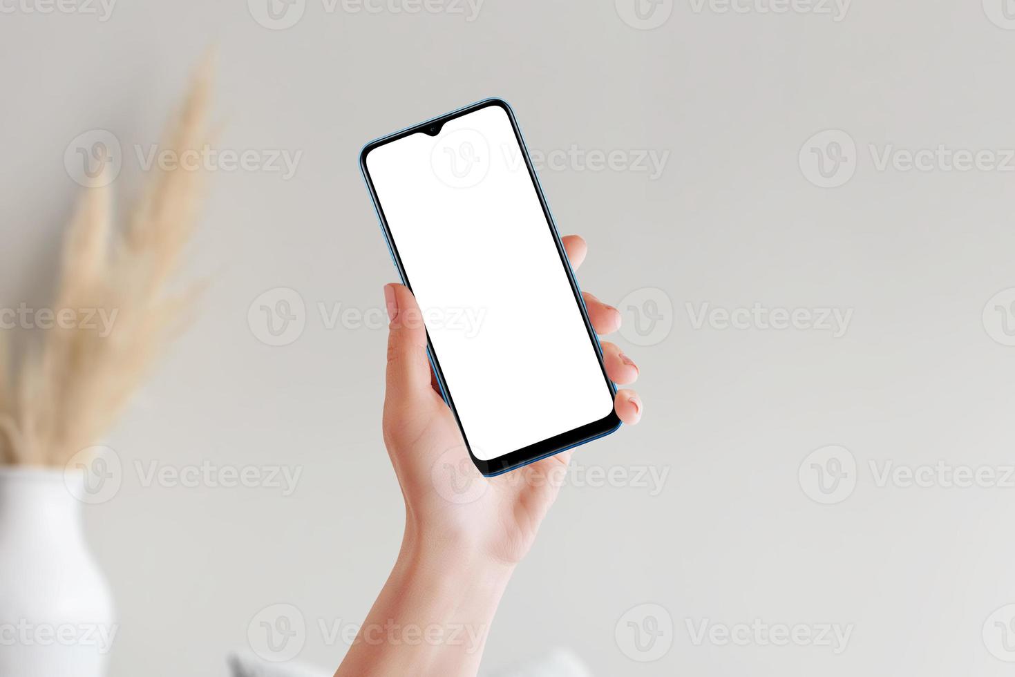 mano femenina sosteniendo un teléfono inteligente con pantalla de maqueta en blanco foto