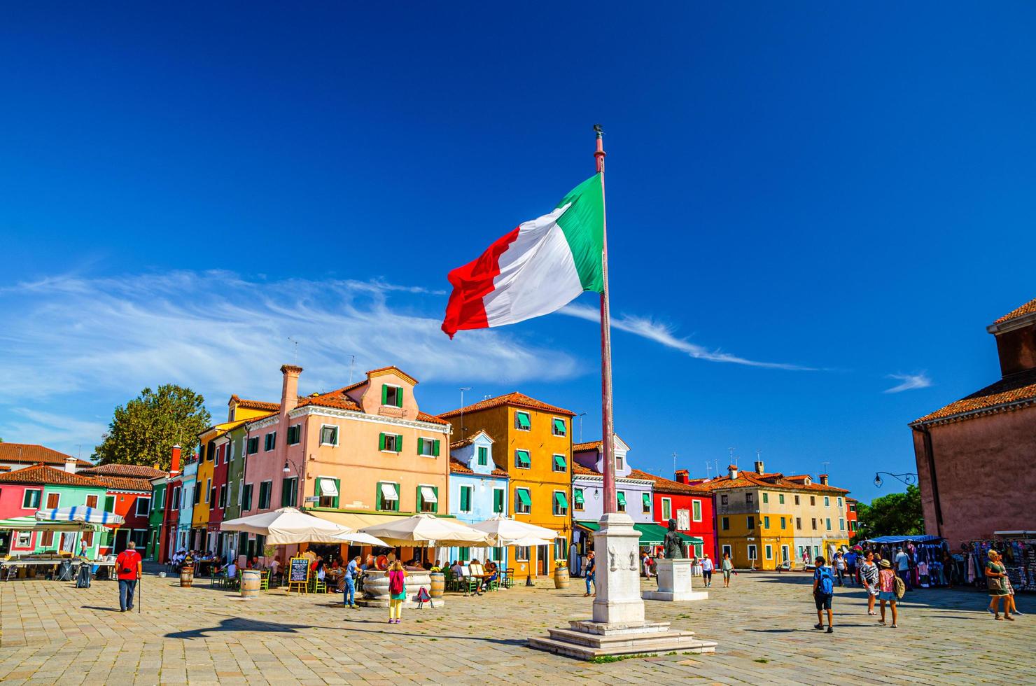 burano, italia, 14 de septiembre de 2019 plaza central de la isla de burano con edificios antiguos y coloridos y bandera italiana ondeando foto