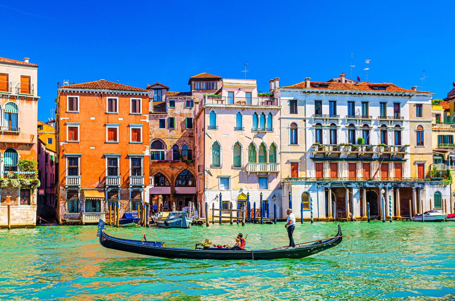 Gondolier and tourists on gondola traditional boat sailing on water of Grand Canal in Venice photo