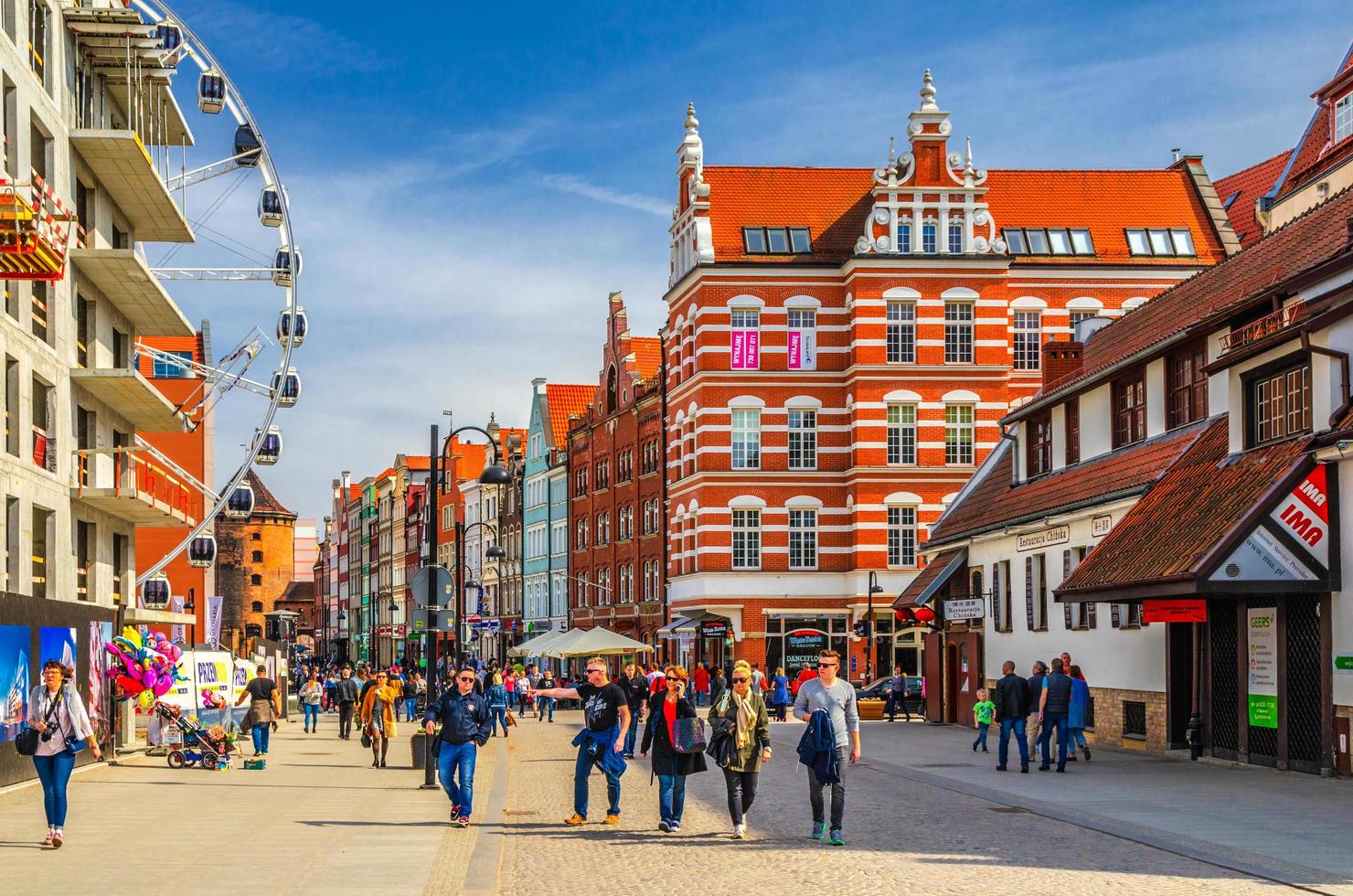 people walking down pedestrian street near big ferris wheel, traditional typical houses buildings in Wroclaw photo