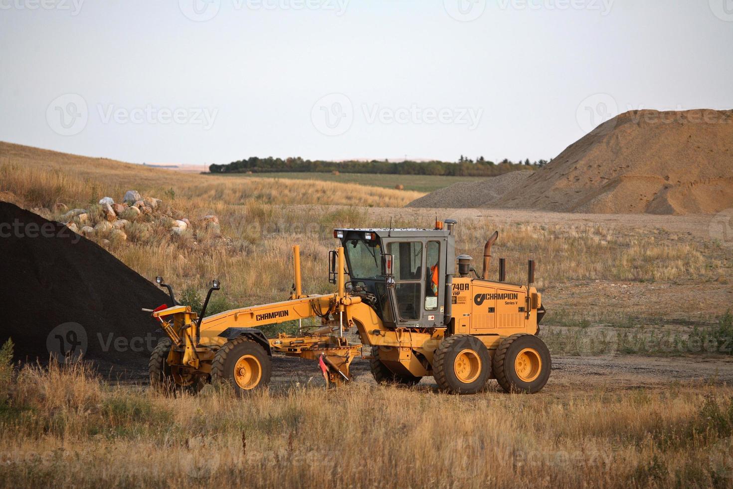 Grader by asphalt pile in scenic Saskatchewan photo