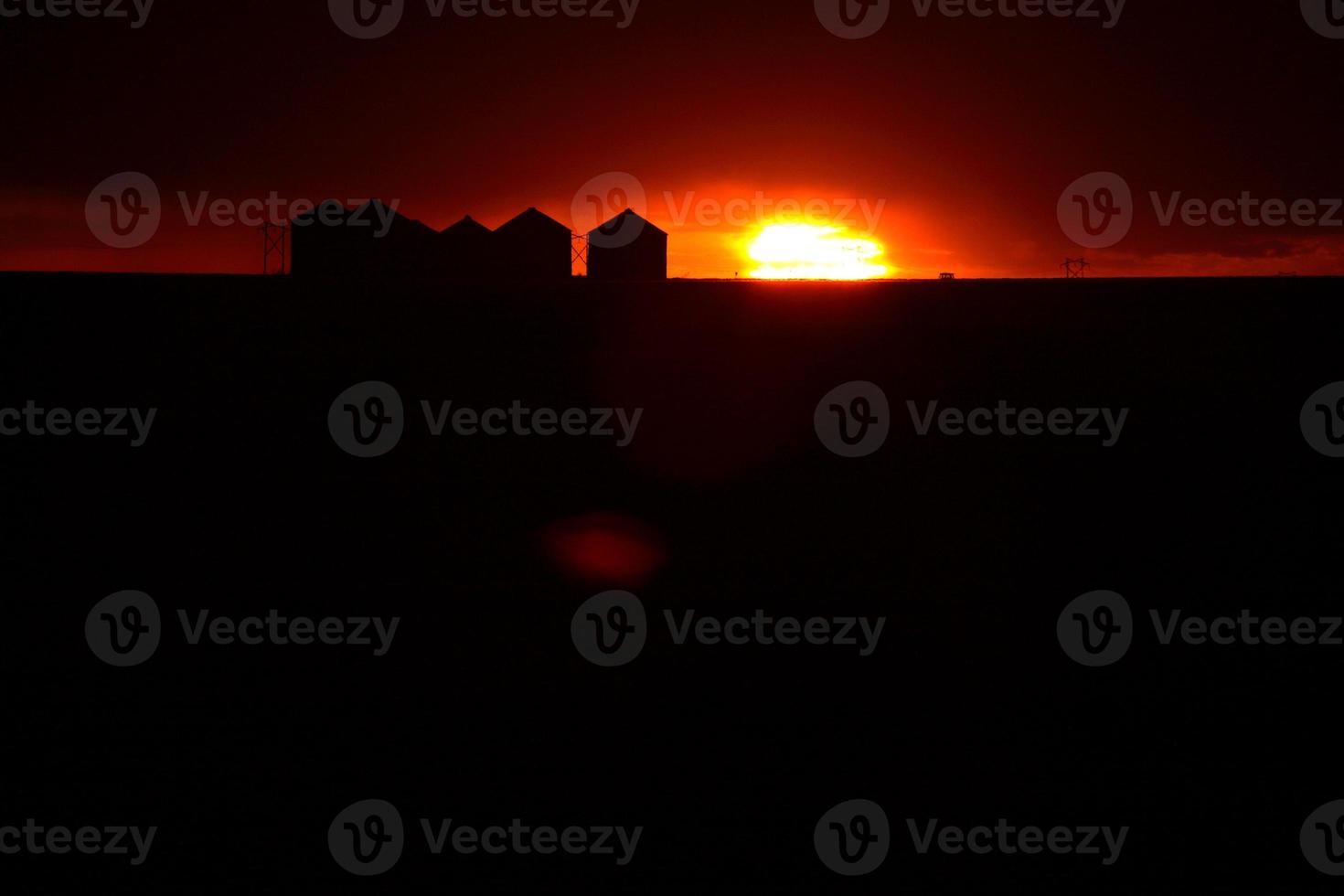Sun setting behind metal granaries in Saskatchewan photo