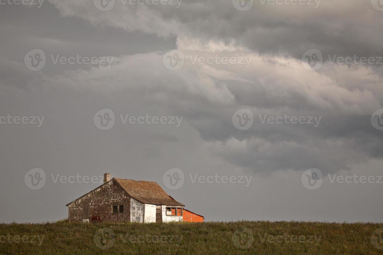 Storm clouds over an old Saskatchewan farm house photo