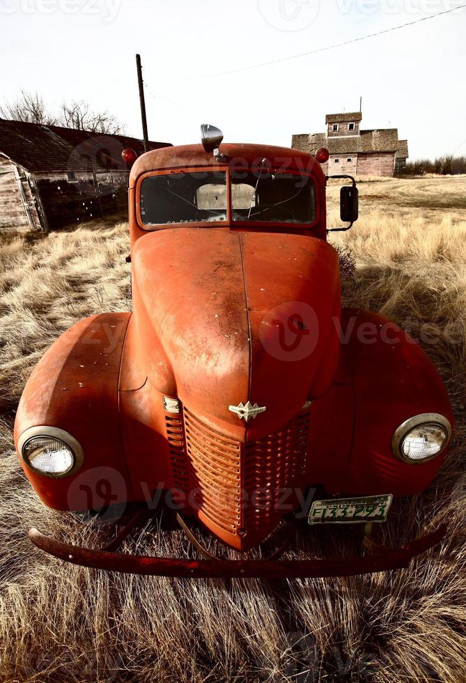 Old farm truck abandoned near unused wooden buildings photo