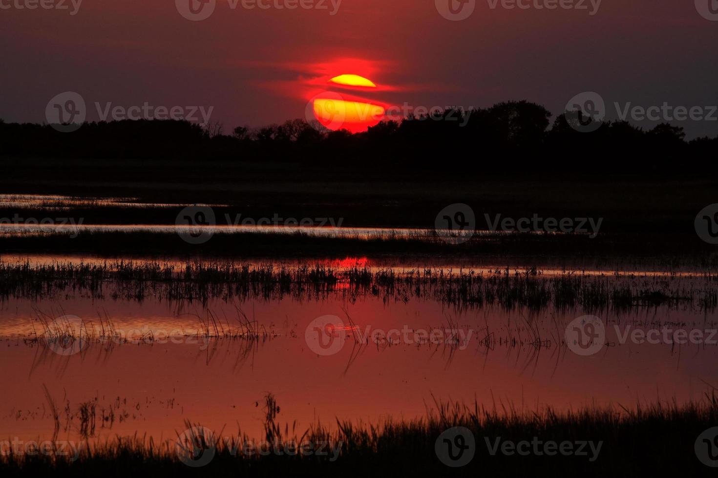Setting sun reflecting off Saskatchewan pond photo