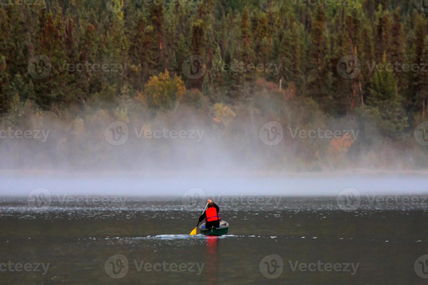 Man in canoe near morning mist on lake photo