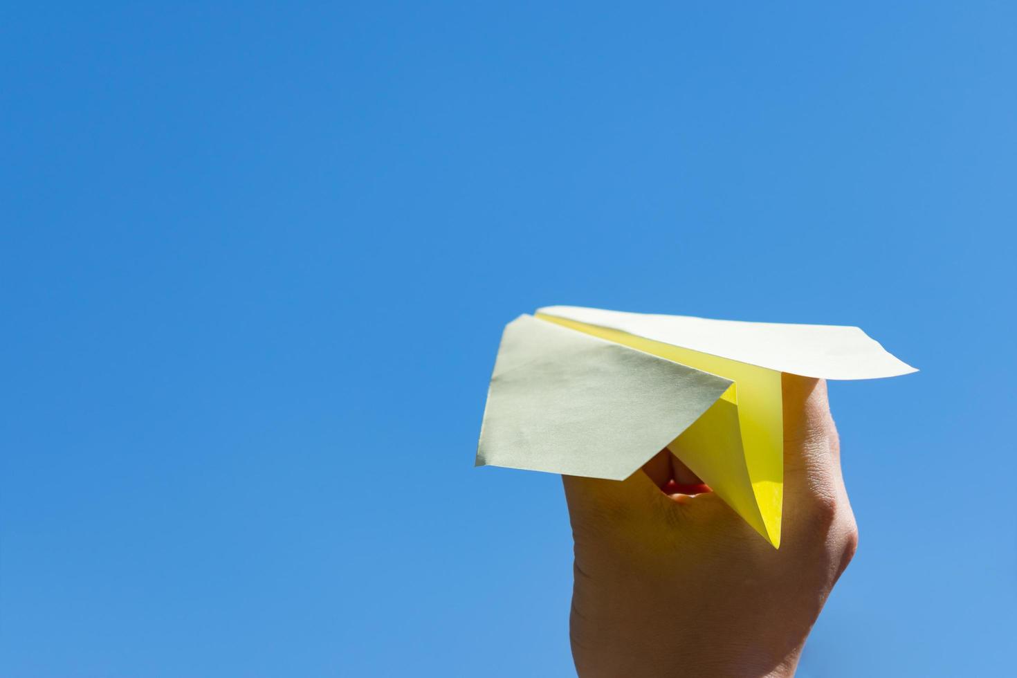 A man launches a paper plane into a clear sky as a symbol of peace and freedom, as well as success and a hobby photo