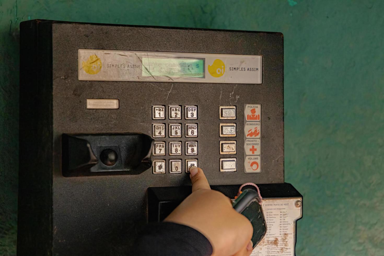 Person dialing phone number at payphone photo
