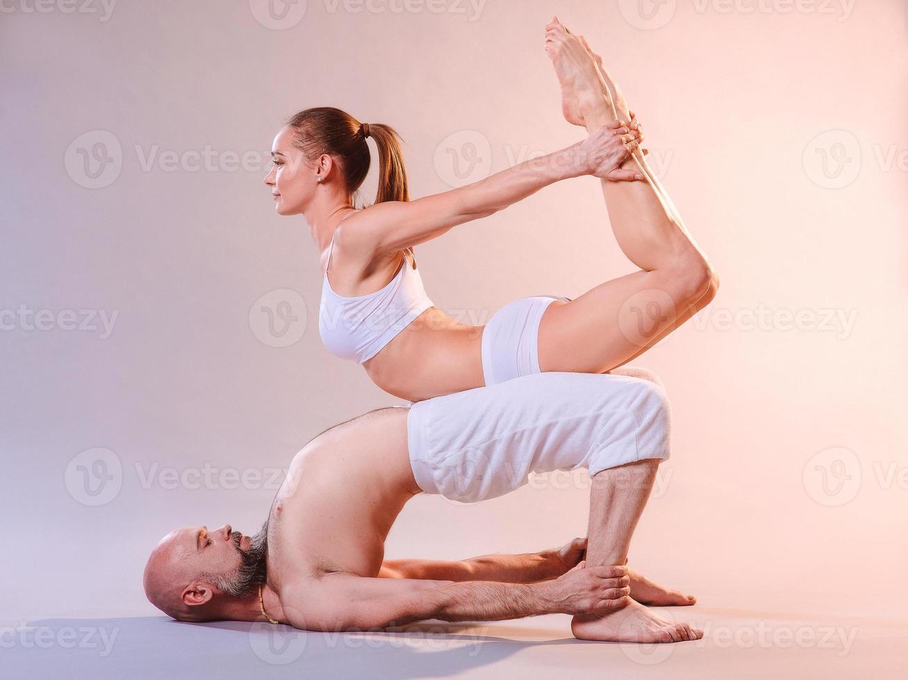 Beautiful sporty woman and man in white clothes doing yoga asanas together indoor photo