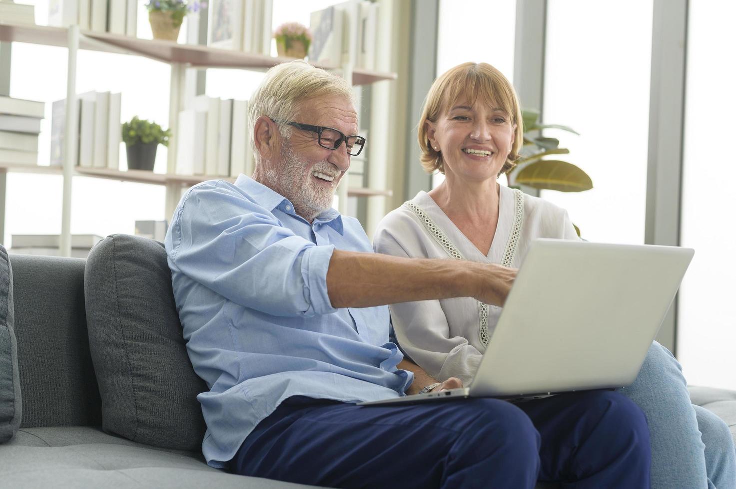 Happy Caucasian senior couple using laptop at home photo